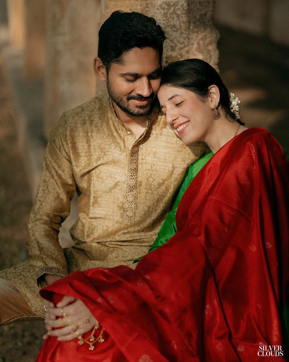 Foreheads together, a red silk saree against gold